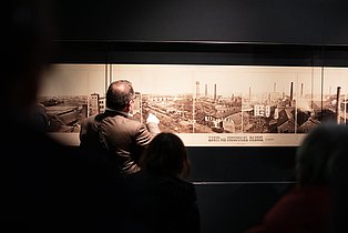 Besucher*innen betrachten ein Exponat in der Dauerausstellung.