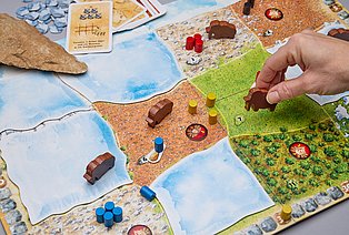 Eine Hand bewegt Figuren auf einem Brettspiel.