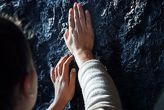 Führung für Menschen mit Sehbehinderung. Nahaufnahme einer Besucherin, welche einen steinernen großen Gegenstand ertastet..