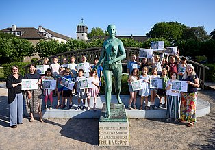 Gruppenbild mit einer Schulklasse der Schule an der Waldlehne und den Macher:innen der Schatzkarte an der Statue "Die Säerin" auf der Margarethenhöhe