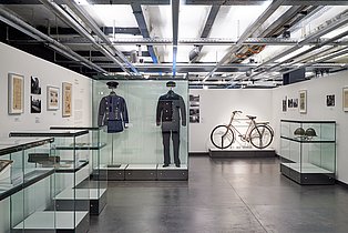 Das Foto gibt einen Einblick in die Ausstellung "Hände weg von der Ruhr! Die Ruhrbesetzung 1923-1925" und zeigt einige der ausdrucksstarken Exponate, wie Uniformen oder das Fahrrad eines Soldaten.