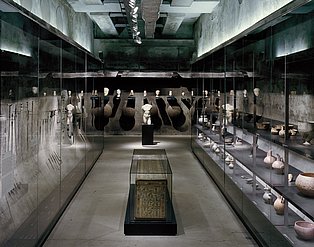 Blick auf verschiedene archäologische Objekte wie ein Sarkophag, Vasen, Werkzeuge und Büsten in Ausstellungsvitrinen auf der 12-Meter-Ebene der Dauerausstellung des Ruhr Museums
