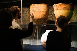 Besucher*innen betrachten eine Vitrine in der Dauerausstellung.