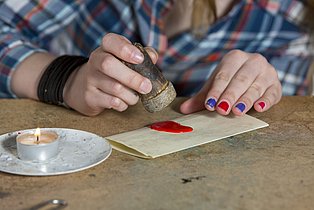 Nahaufnahme eines Kindes, das mit Wachs einen Brief versiegelt.