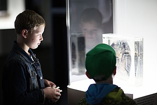Zwei Kinder betrachten ein erleuchtetes Exponat in der Dauerausstellung des Ruhr Museums.
