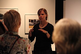 Guide führt Menschen in Gebärdensprache durch eine Ausstellung.