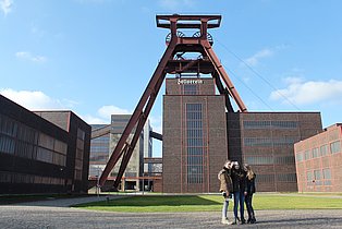 Three young visitors take a selfie in front of the Doppelbock on the grounds of Zollverein.