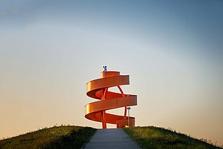 Schacht Franz, Lippepark Hamm Foto von der orangen freistehenden Treppe, die eine Kunstinstallation auf der Halde im Lippepark Hamm ist.