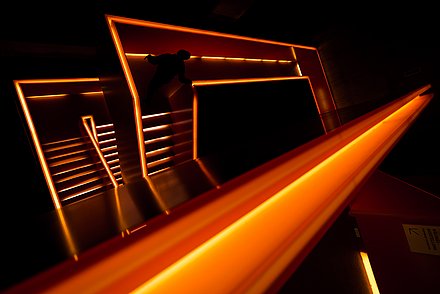Das in orangenes Licht getauchte Treppenhaus des Ruhr Museums im Innenbereich.