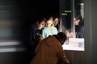 Besuchergruppen von Kindern und Erwachsenen betrachten ein Exponat in der Dauerausstellung des Ruhr Museums.