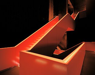 Das Treppenhaus des Ruhr Museums in orangenes Licht getaucht.