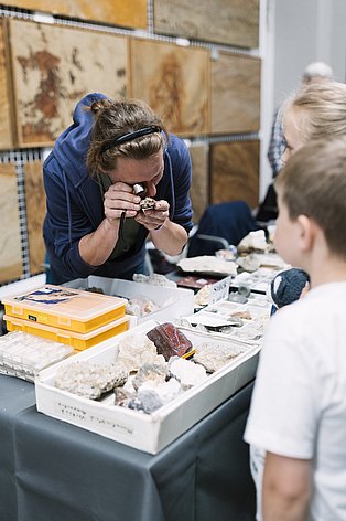 Eine Person untersucht mit einer Lupe Mineralien
