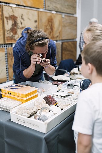 Eine Person untersucht mit einer Lupe Mineralien