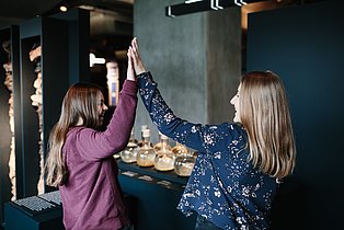 Two visitors high-five each other and rejoice in the permanent exhibition.