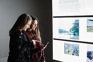 Zwei Besucherinnen rätseln in der Dauerausstellung mit der BIPARCOURS-App vor einem Exponat.