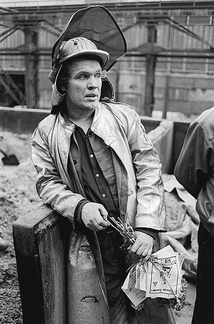 Schwarz-Weiß-Bild eines Arbeiters mit Helm und Anzug auf der Thyssen Henrichshütte AG in Hattingen.