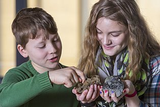 Workshop "Kohle"  Zwei Kinder halten zwei Steine in ihren Händen.