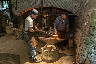 Zwei Schmiede bearbeiten ein glühendes Eisen