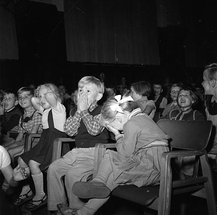 Kinder lauschen sitzend spannenden und lustigen Geschichten im Rahmen der Stadtranderholung 1957.