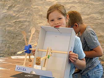 Ein Kind hält etwas Gebasteltes in den Händen